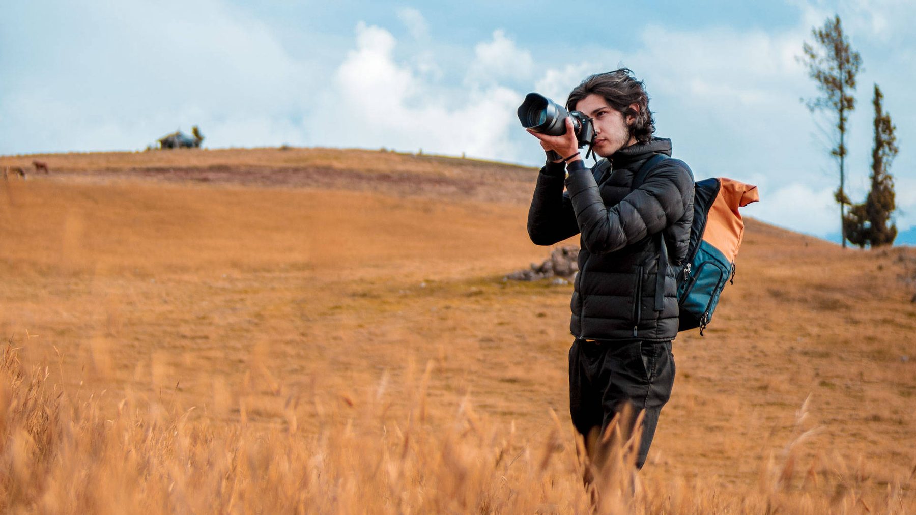 Juan David Galvis walking a golden field with his camera