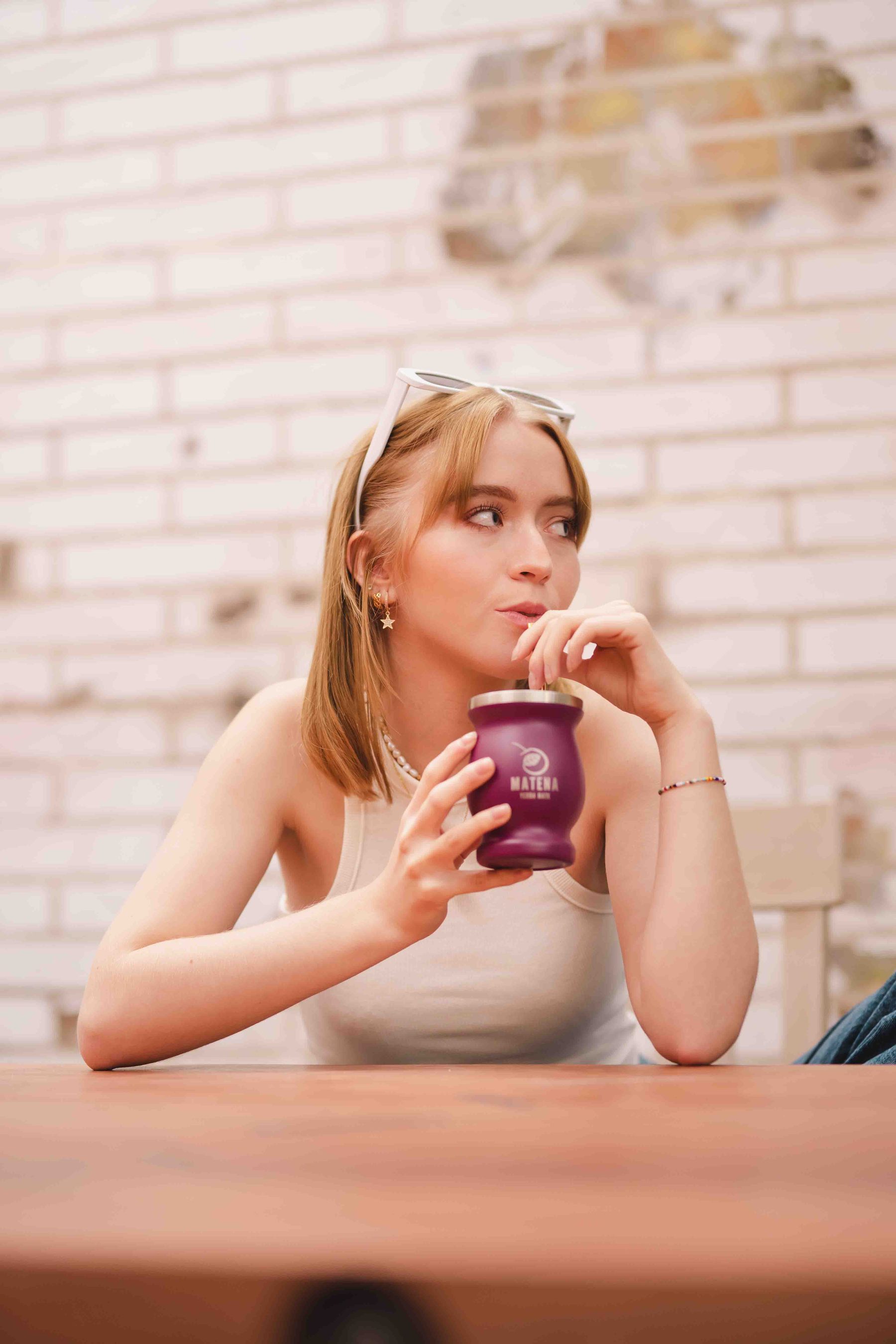 Woman with a drink against white brick