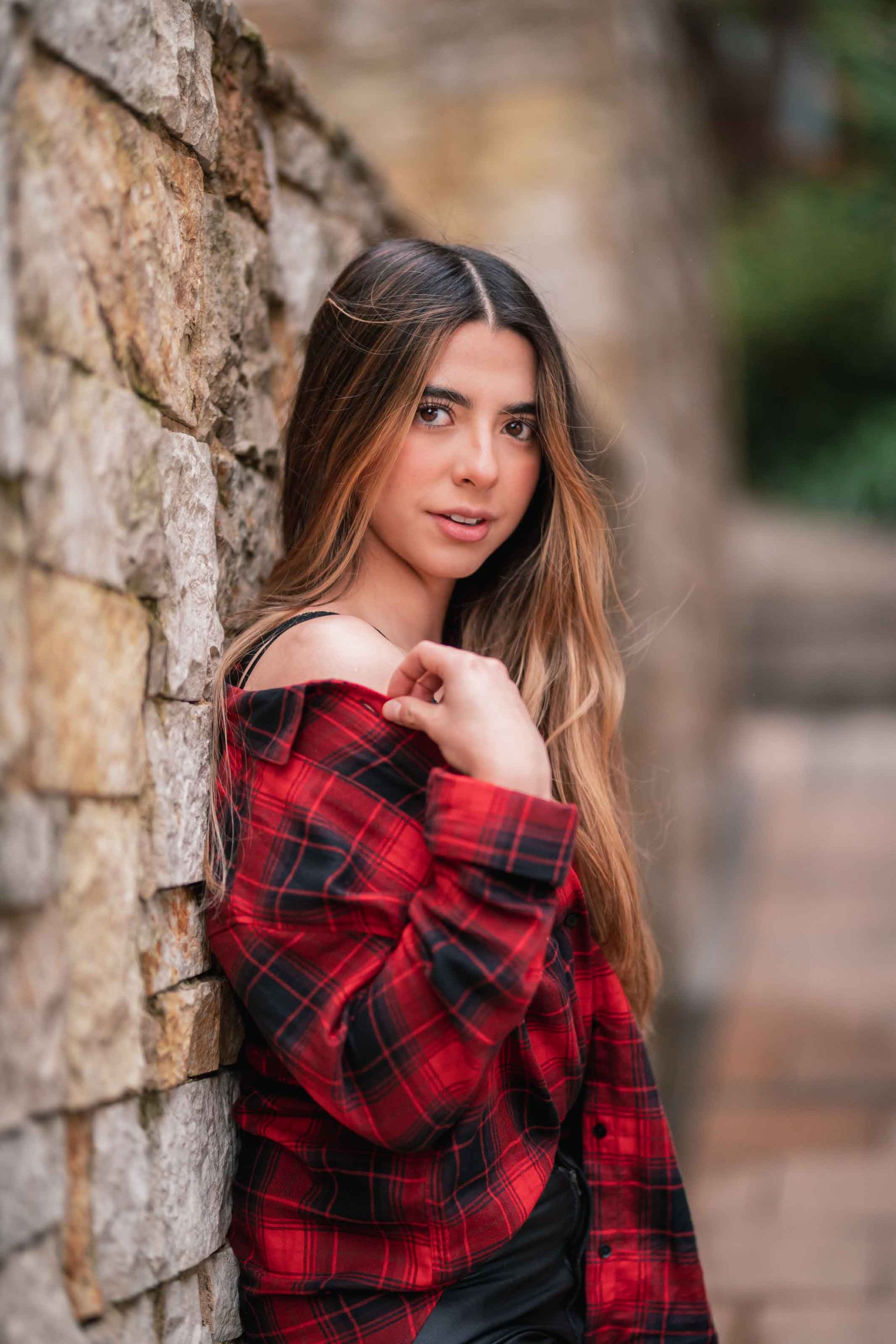 Woman in red plaid against a stone wall