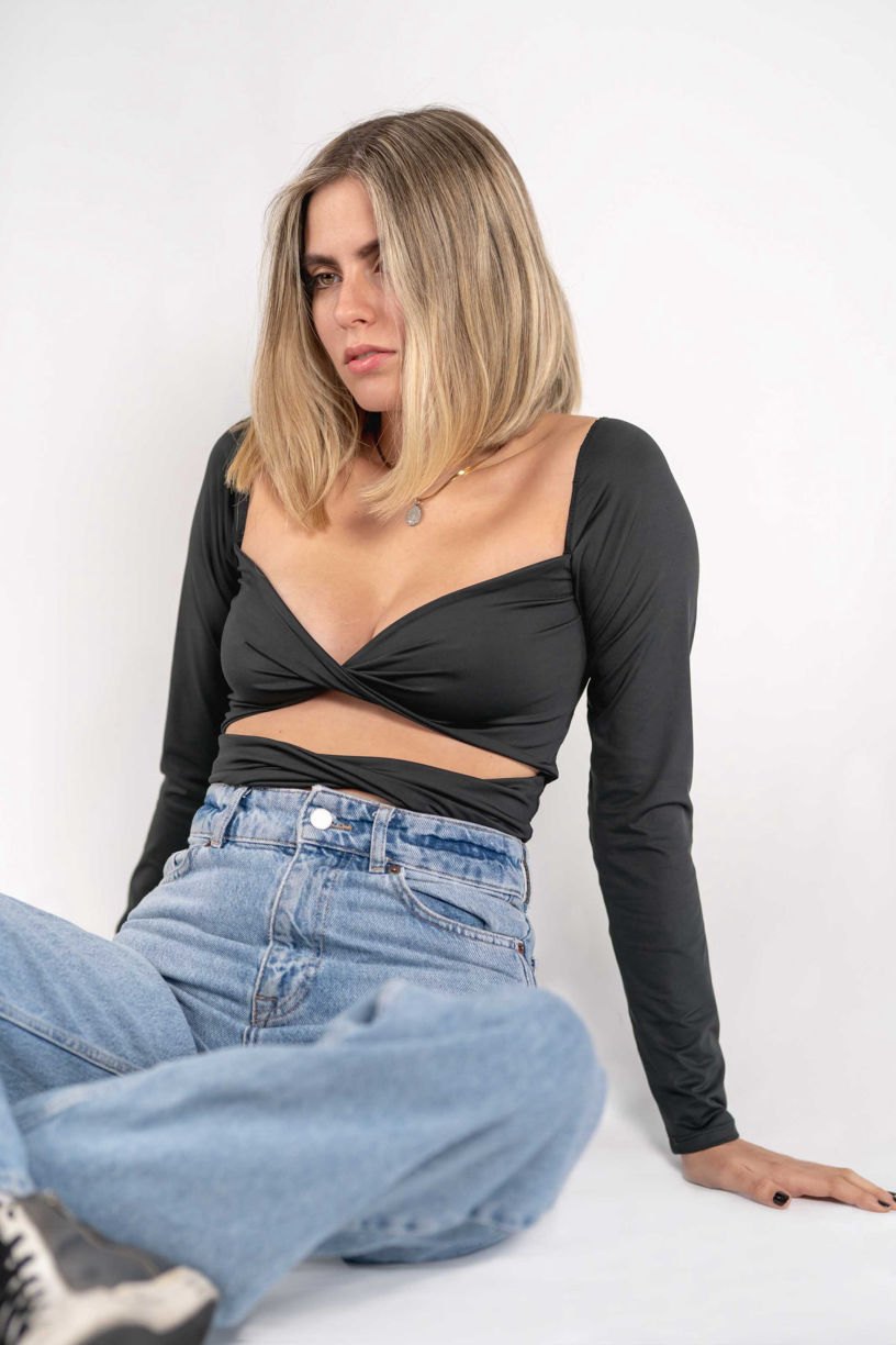 Model seated on the floor in a black twist top