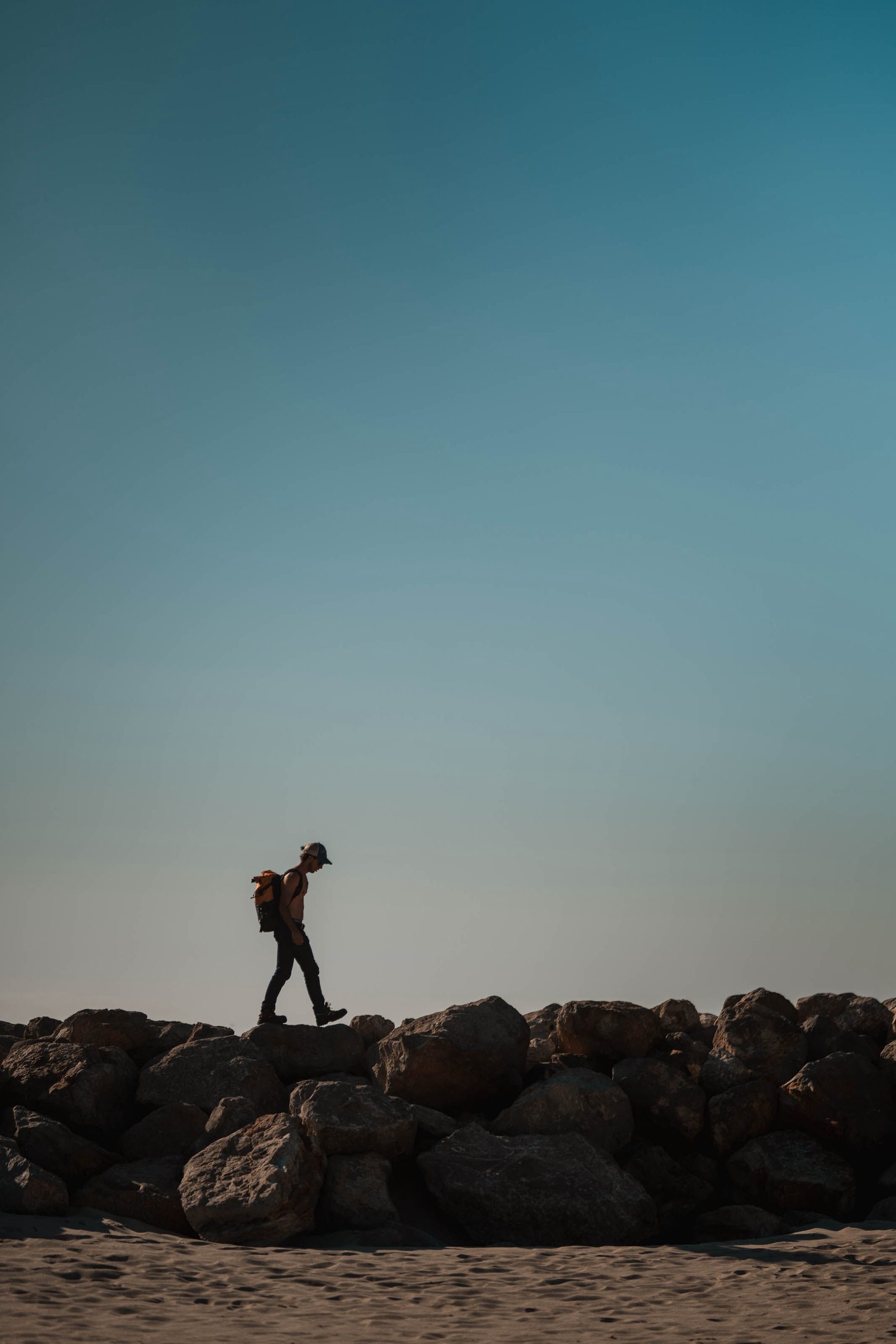 Lone walker on a rock wall against the sky