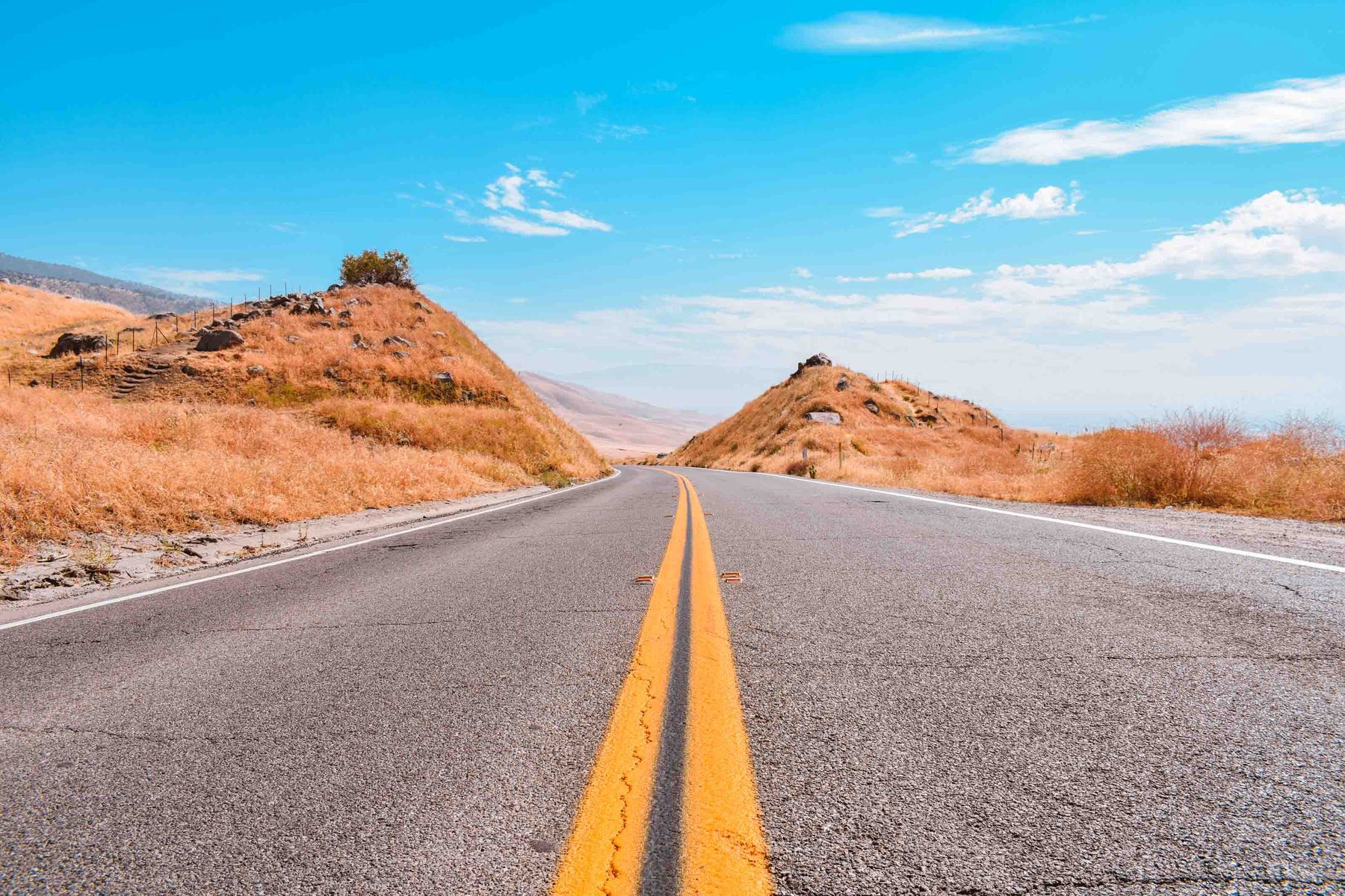 Yellow line road through dry hills