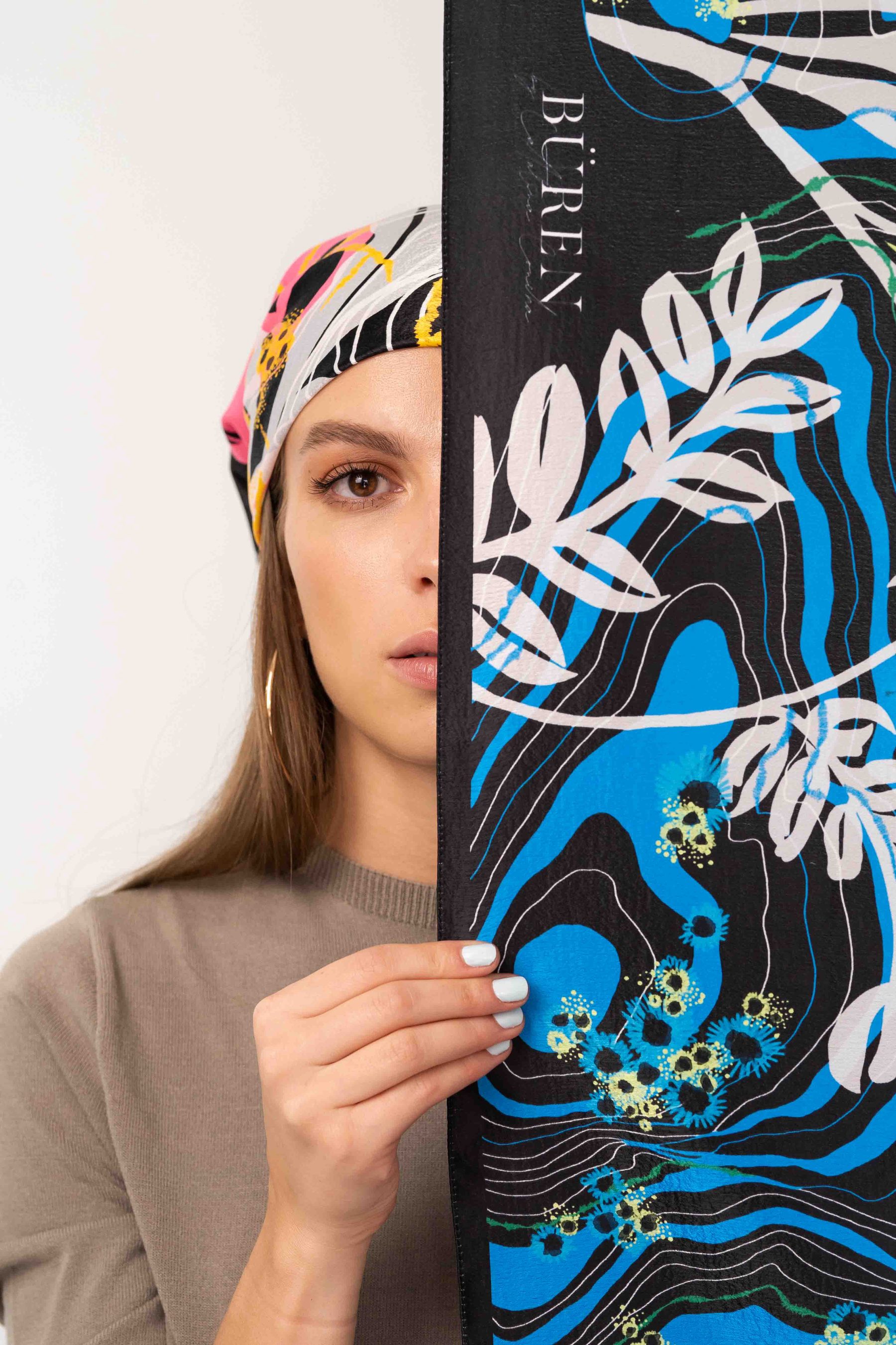 Model covering half her face with printed art